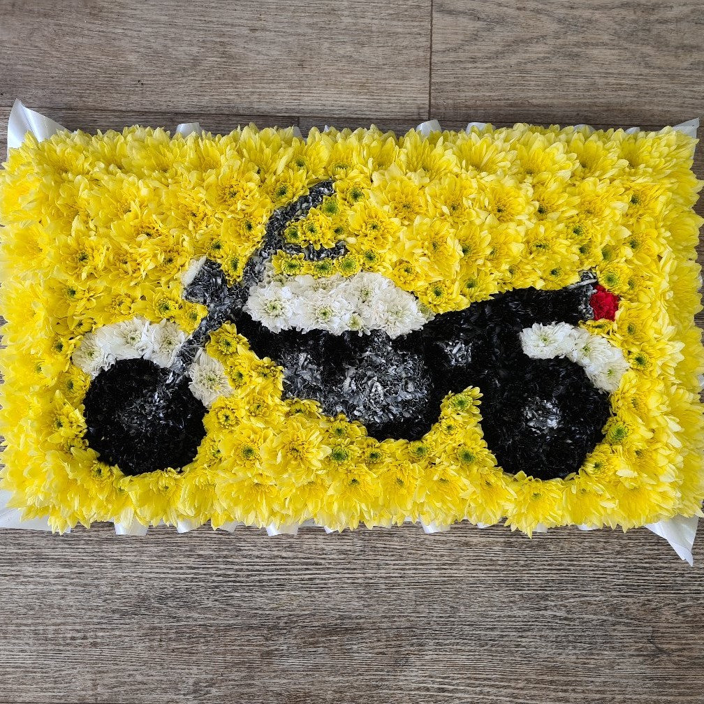 A flower arrangement shaped like a motorbike with  a yellow background
