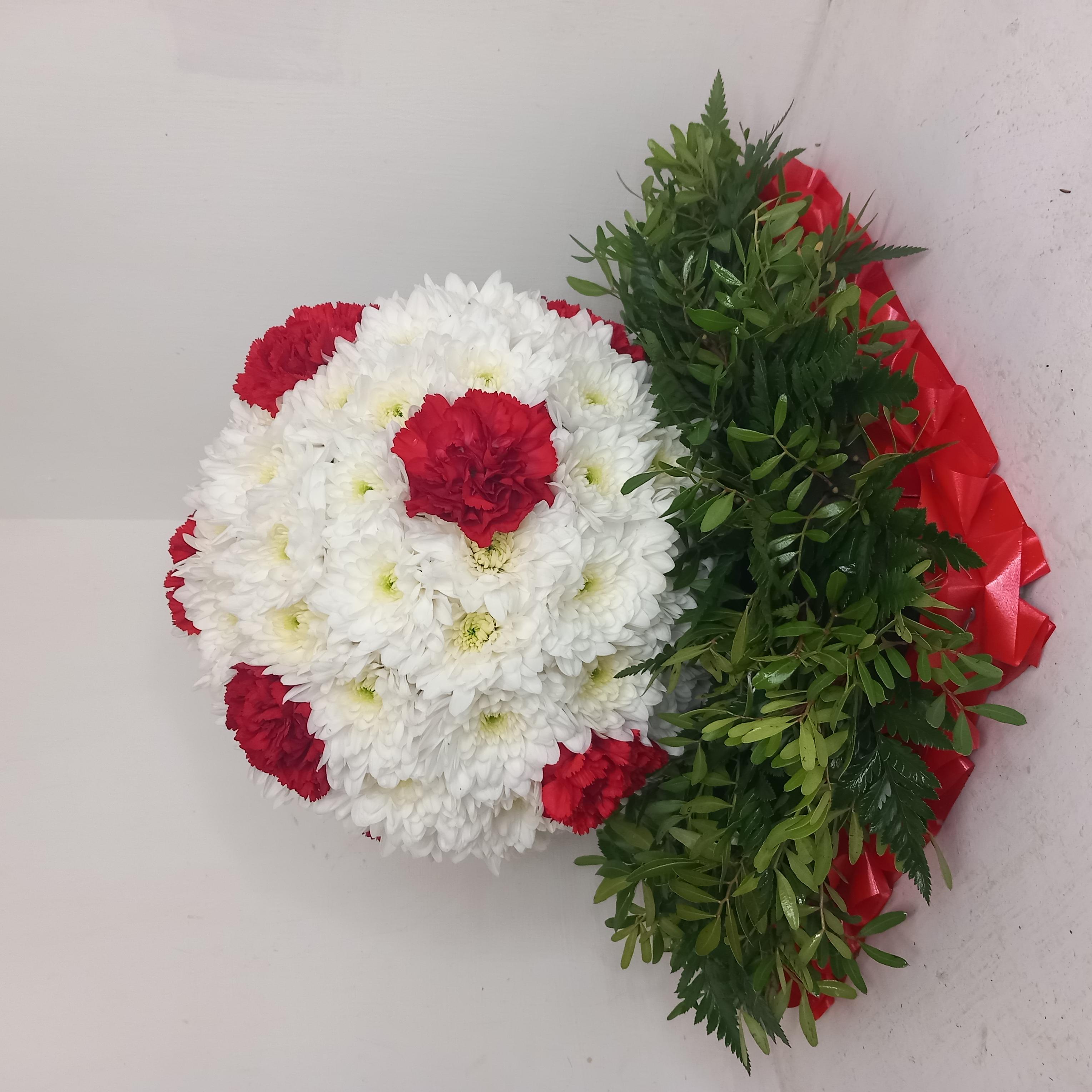 A 3D football made of white and red flowers, resting on a greenery base.