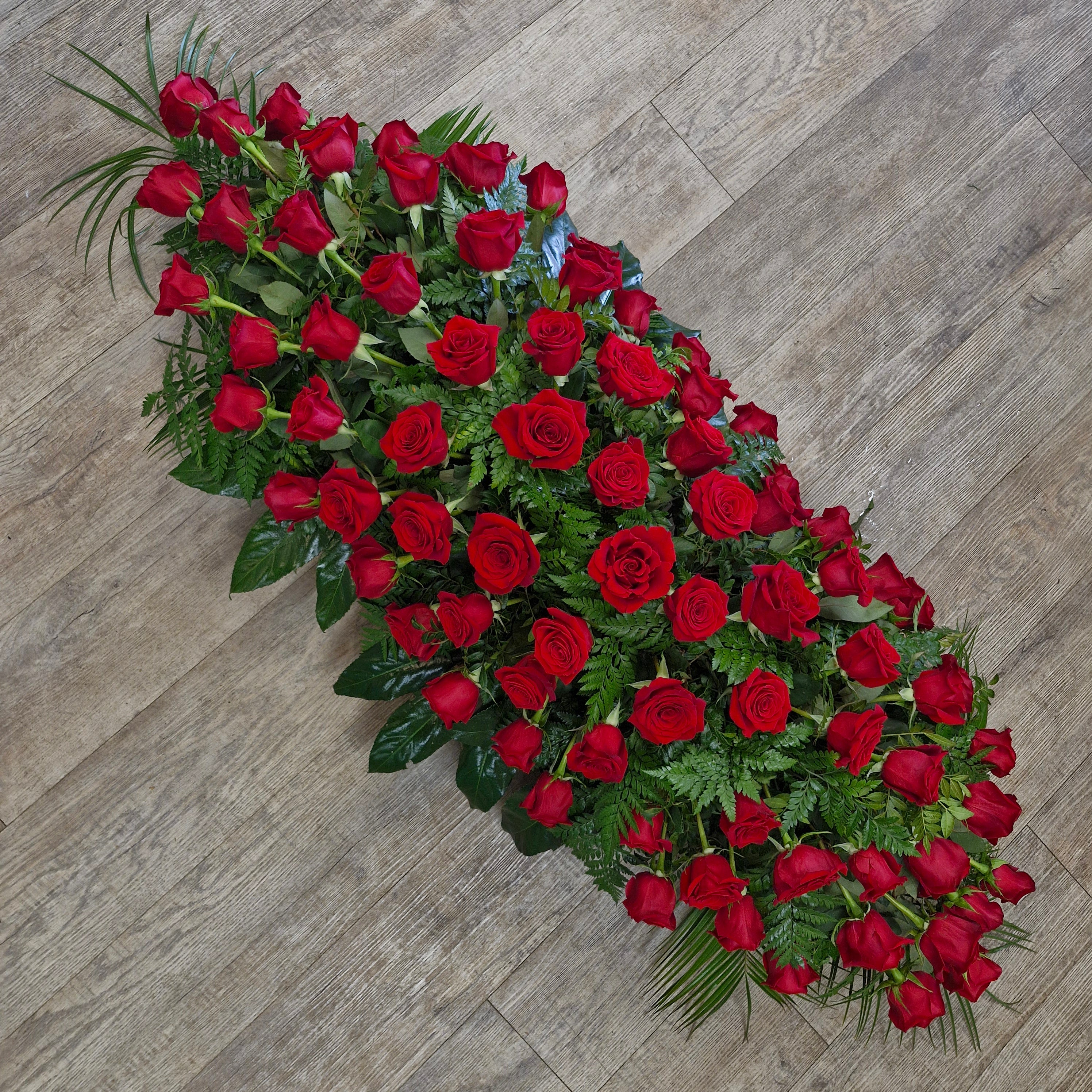 A long floral arrangement of red roses with green foliage