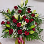 A floral arrangement featuring red roses, white lilies, white gypsophilia, and mixed greenery, arranged in oasis foam in a box.