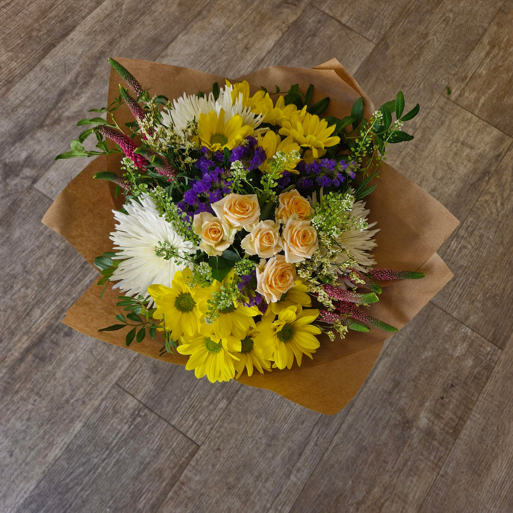 A handtied bouquet of flowers available in different colours and wrapped in brown paper.