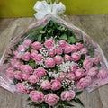 A bouquet of roses with gypsophila and mixed greenery, wrapped in cellophane and tied with a bow
