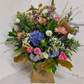 A medium-sized box arrangement featuring a variety of natural-looking flowers in a mix of colors, arranged in a natural style.