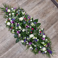 A floral arrangement of purple callas and white roses with green foliage, designed as a 4ft double-ended coffin spray.