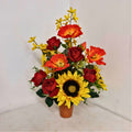 An upright cement pot with a bouquet of artificial flowers that include sunflowers, roses, and other colorful flowers.