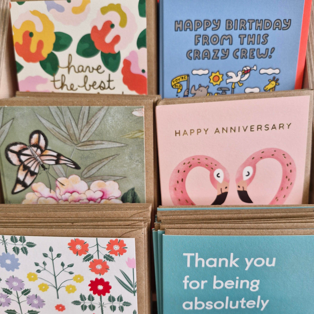 A variety of greeting cards with different designs, including some with floral patterns and animal illustrations, displayed in a card holder.