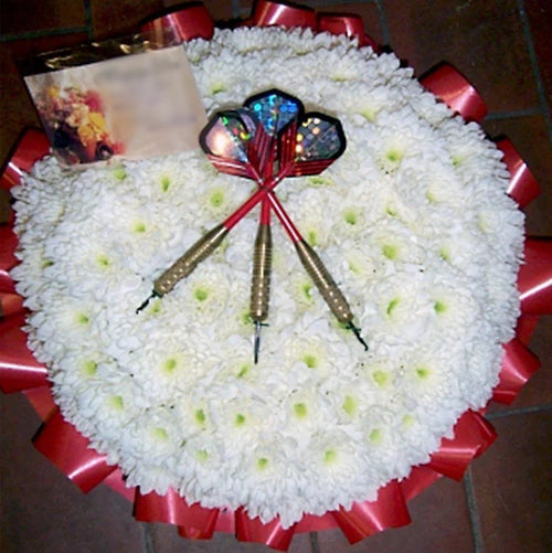 A 12-inch darts-themed posy pad with a group of darts in the centre, surrounded by white flowers and decorative ribbon edge.
