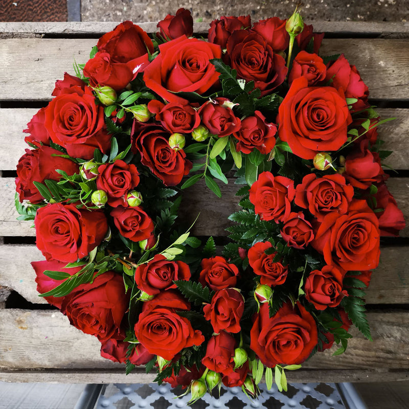 A round red rose wreath made of different sized roses.