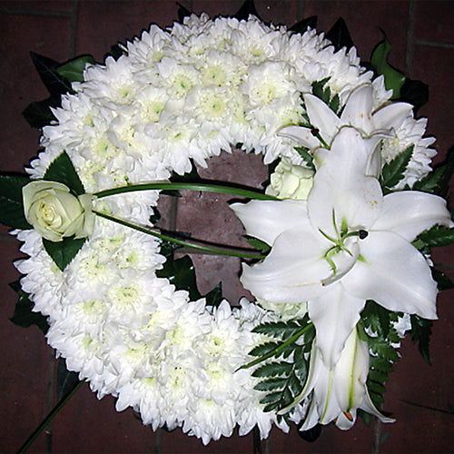 A 10 inch white ring wreath with a greenery edge and lily spray