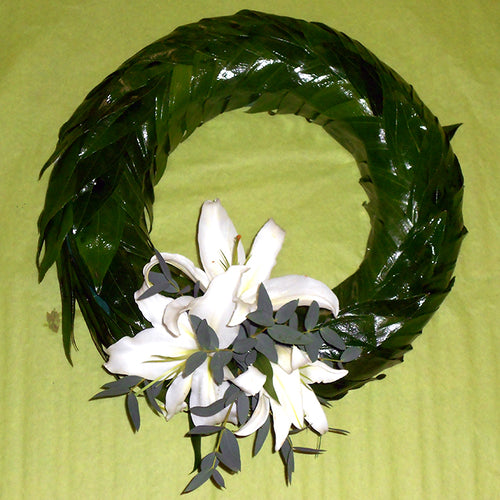 A 12-inch green foliage wreath with a white lily spray in the center