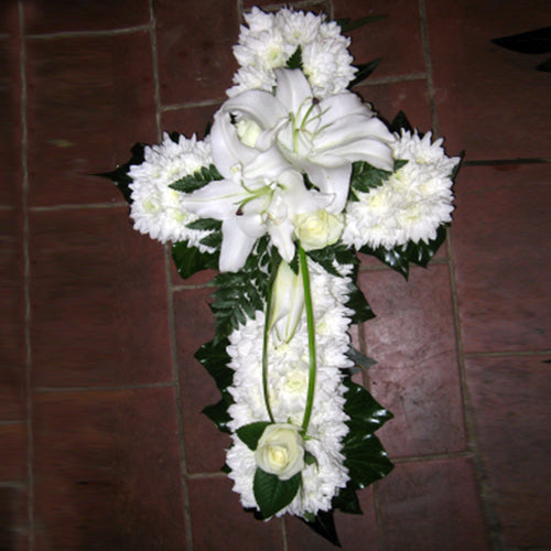A white massed cross with lily spray