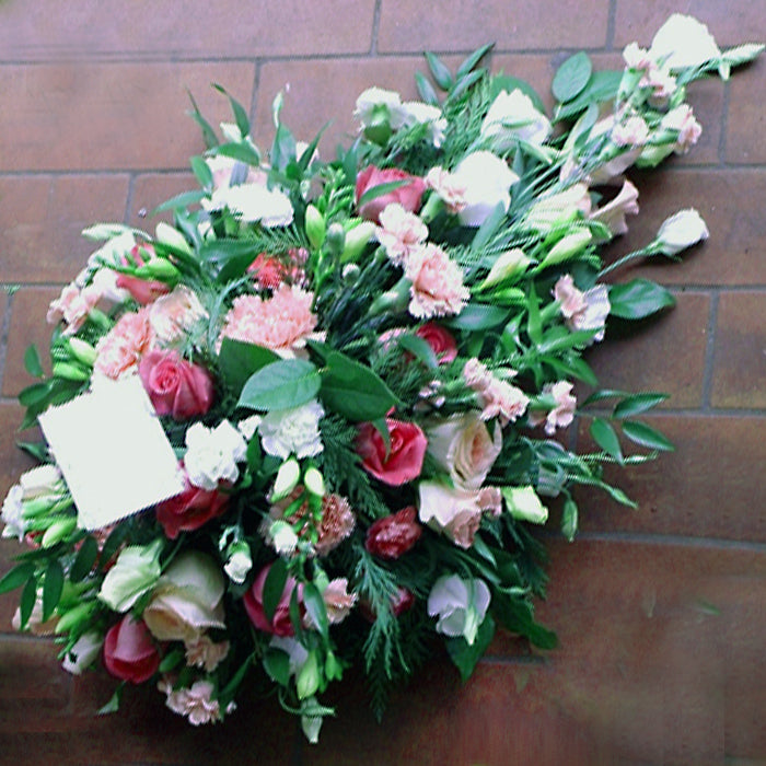 A teardrop-shaped floral arrangement featuring a mix of pink and white flowers with green foliage.