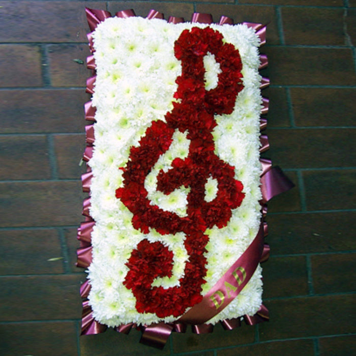 A floral arrangement in the shape of a music note with red and white flowers.