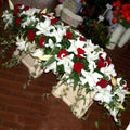 A coffin spray featuring a mix of large headed roses and open white lillies
