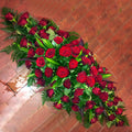 A coffin top arrangement with red roses and green foliage