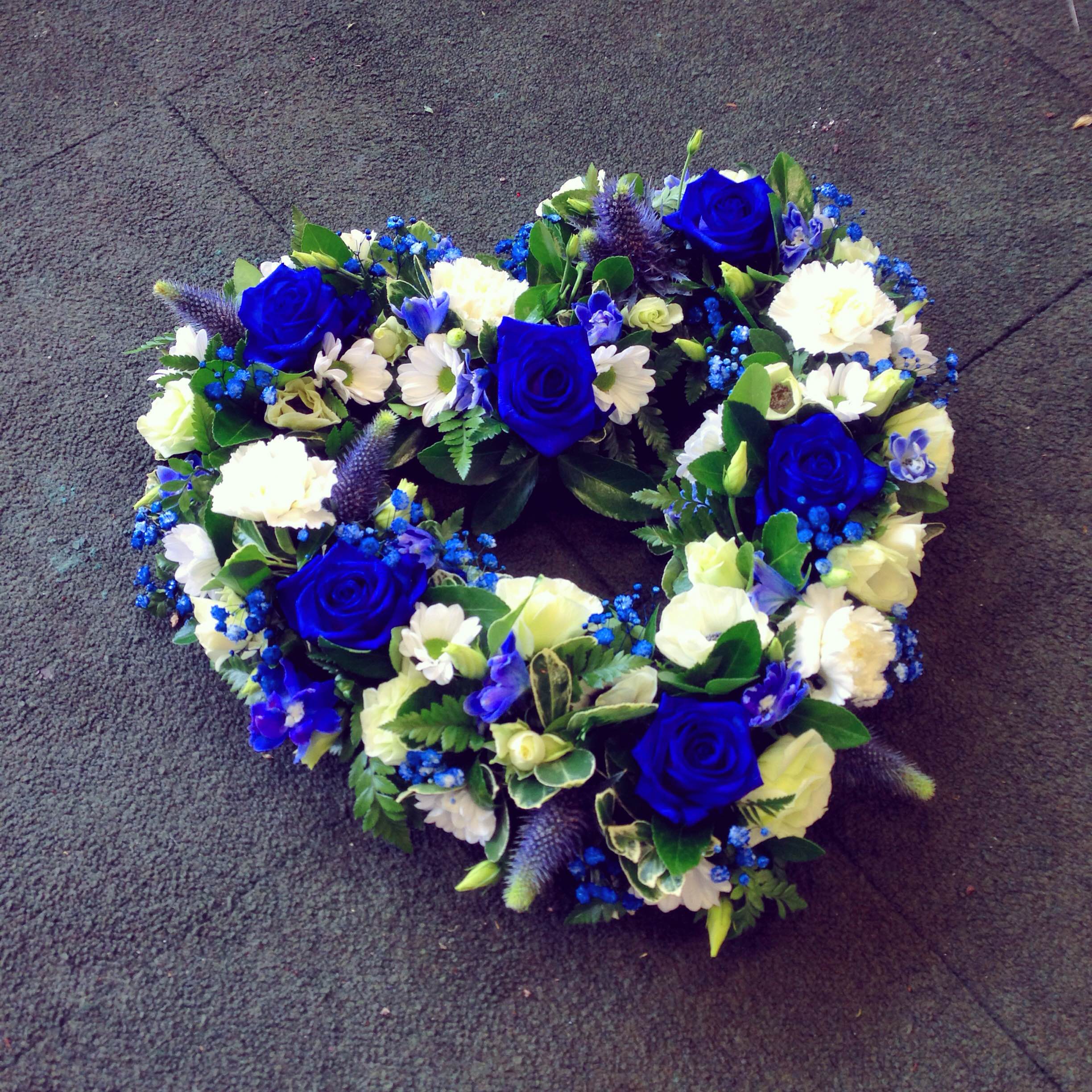 A 15 inch open heart-shaped wreath arrangement with a combination of blue and white flowers