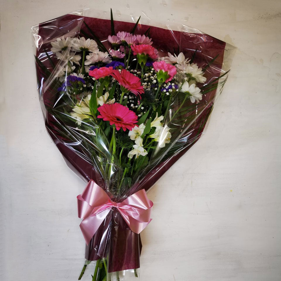 A bouquet of flowers including shades of pink, white, and green, tied with a ribbon and presented in a clear packaging.