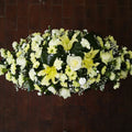 A traditional casket spray with cream and white flowers