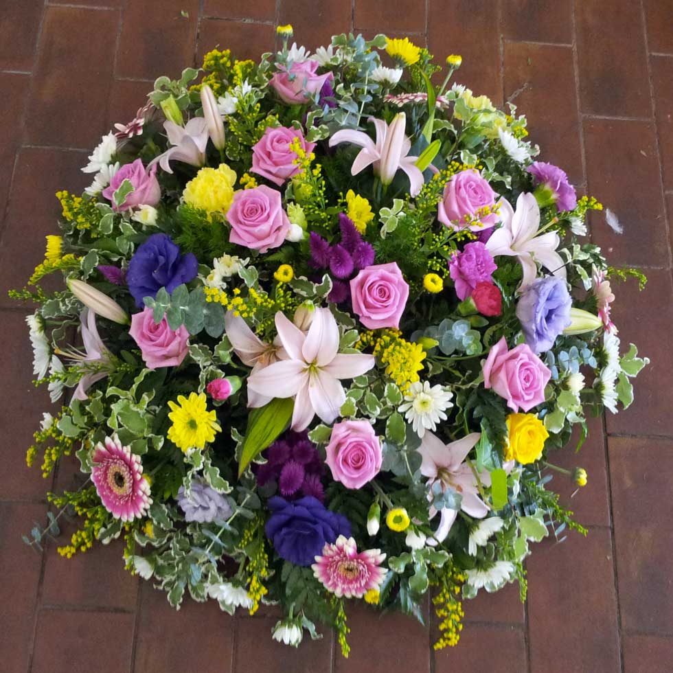 A large tribute posy of assorted spring-colored flowers