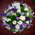 A floral posy with a variety of flowers in mauve and lilac, arranged in a posy