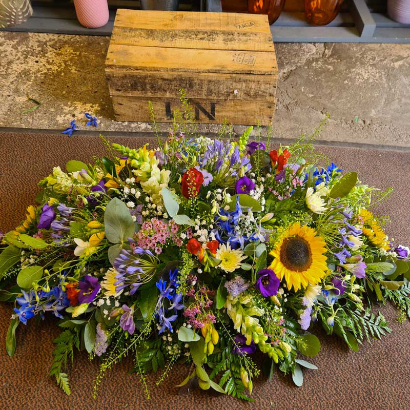 A floral arrangement, consisting of a variety of seasonal flowers in shades of blue, red, and yellow.