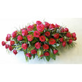 A floral casket spray with red roses and green leaves