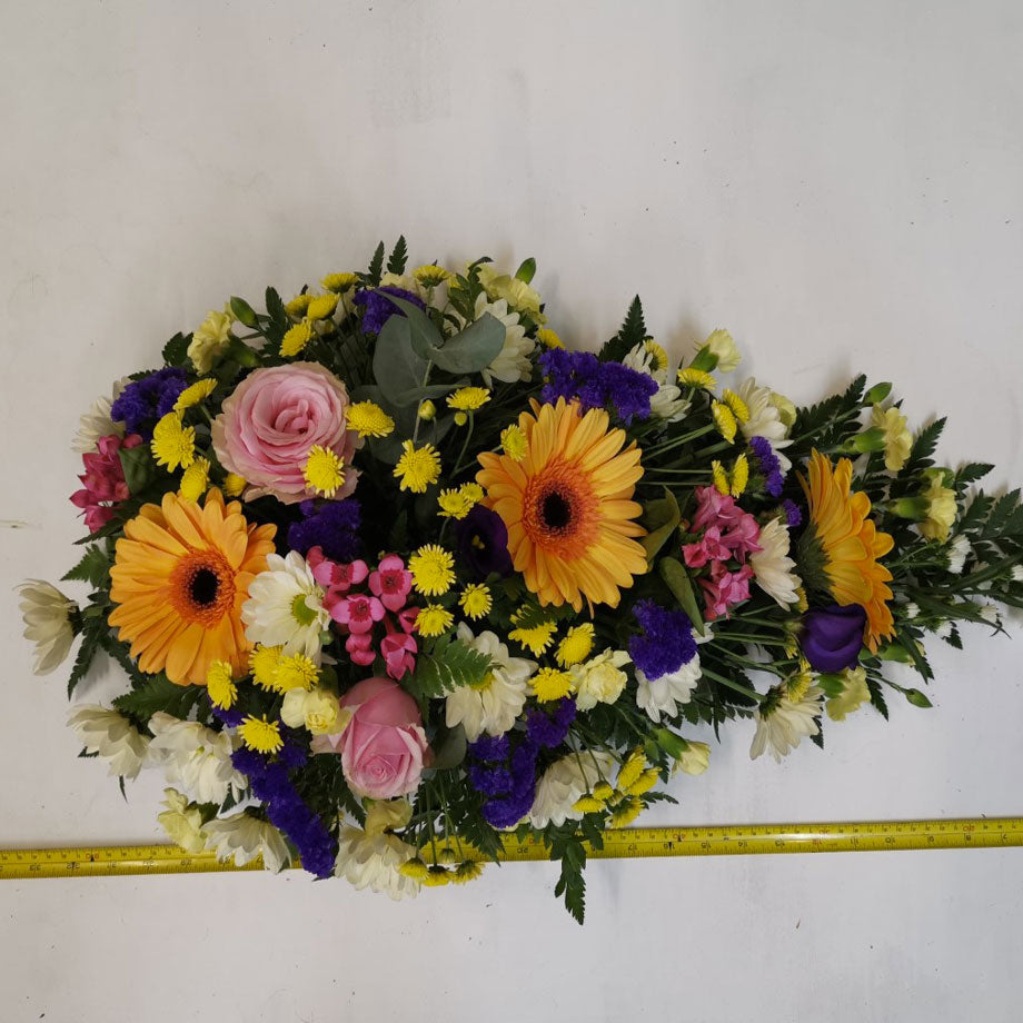 A teardrop-shaped floral arrangement with a variety of summery colourful flowers 