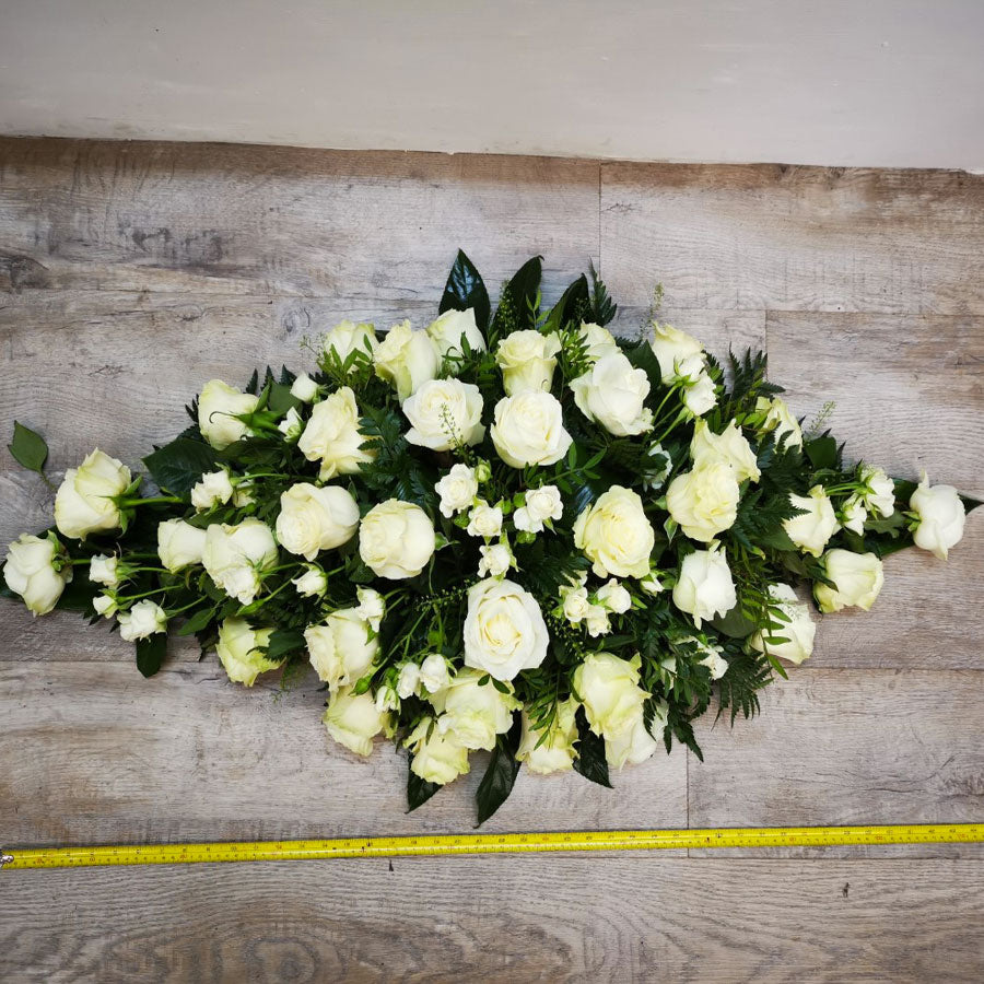 A casket spray made up of white roses of varying sizes