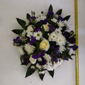 A round arrangement of purple and white flowers with green foliage edging, approximately 15 inches in diameter.