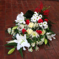 A tied sheaf of red and white flowers, including roses and other seasonal blooms