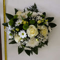 A small white posy flower arrangement featuring white roses, with green leaves